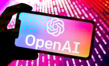 OpenAI logo open on a phone bathed in pink light.