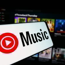 A mobile phone with the logo of American music streaming service YouTube Music is seen in front of business website.